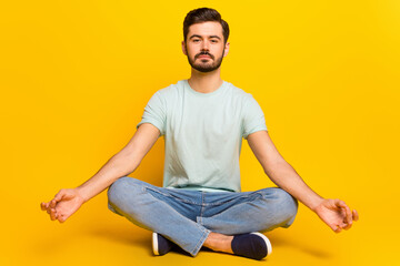 Portrait of attractive calm guy meditating spending free spare time isolated over bright yellow...