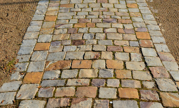cobbled strip of beige brown cobblestone stones. around is a park gravel road of the castle's honorary courtyard. Centrally symmetrical division with lawns and spheres cut into old boxwoods