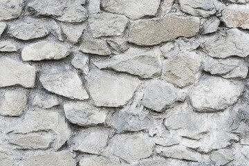 Mosaic stones construction backdrop. Grunge uneven brick wall pattern. Pieces of cracked blocks in concrete wall background. Gray concrete joint. Decorative exterior wall.