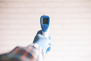 Hand holding infrared thermometer to measuring temperature.