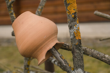 Сlay pot on a fence made of dry branches. Traditional decoration. Landscape design.