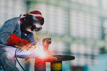 Man welding at the factory by arc weld holder and spark light
