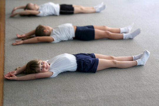 Girls lie on the floor doing stretching exercises