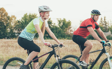 Naklejka premium couple ride bicycles in the summer at the stadium