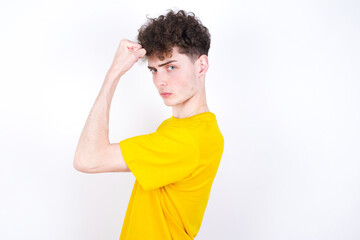 Portrait of powerful cheerful young caucasian handsome man with curly hair wearing yellow T-shirt...