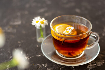 chamomile tea with lemon in a transparent cup on a black background. Breakfast concept, herbal tea.