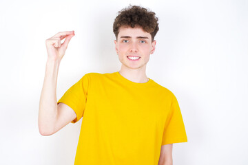 young caucasian handsome man with curly hair wearing yellow T-shirt against white studio background  pointing up with hand showing up seven fingers gesture in Chinese sign language QÄ«.