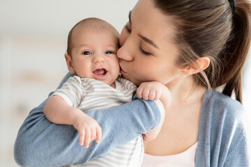 Mother's Love. Closeup Portrait Of Young Mom Kissing Her Cute Newborn Child