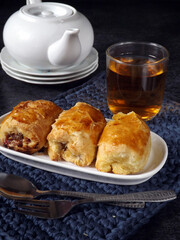 Bolen Pisang or Banana Wrapped with Puff Pastry, typically food or snack from Bandung, Indonesia. Served in white plate on crochet place mat. Popular as Bolen Bandung. Concept of tea or snacking time.