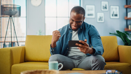 Happy Black African American Man Playing Video Game on Smartphone App and Win, Showing YES Gesture....