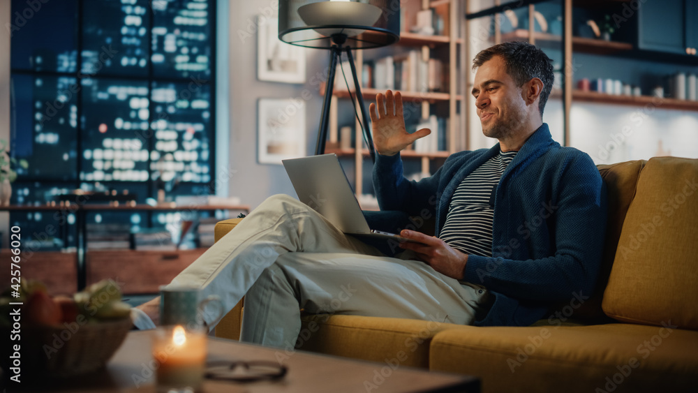 Aufkleber handsome caucasian man having a video call on laptop computer while sitting on a sofa in cozy living