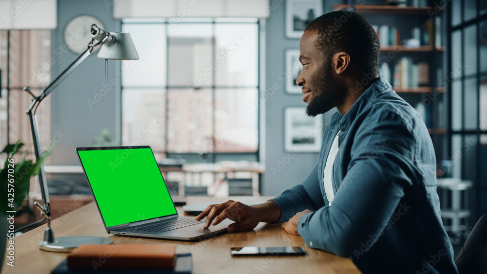 Poster handsome black african american specialist working on laptop computer with green screen mock up disp
