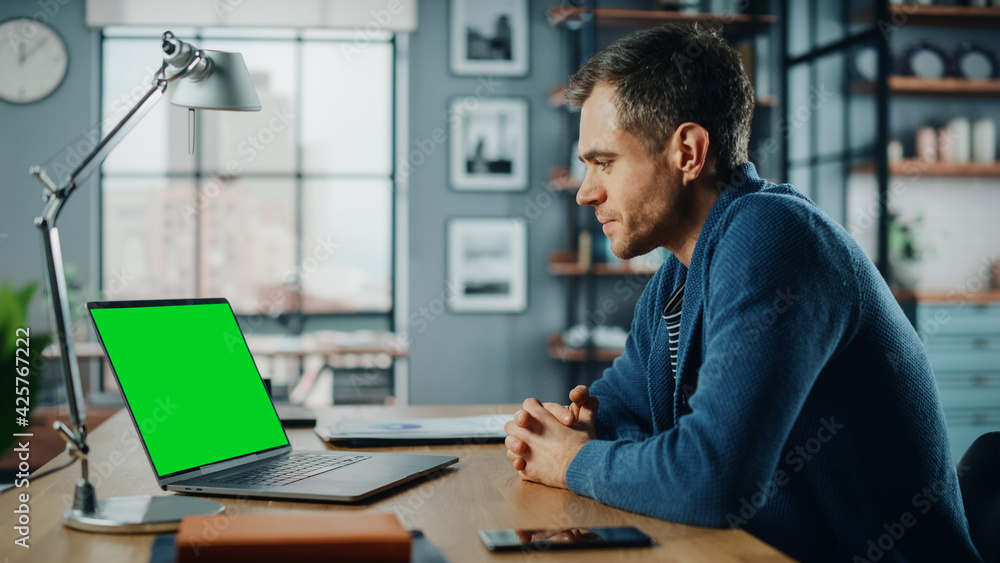Poster handsome caucasian specialist chatting on video call on laptop with green screen mock up display at 