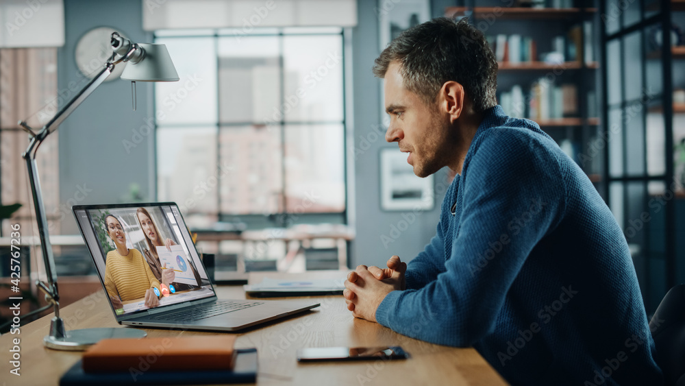 Poster Handsome Caucasian Man Having a Video Call on Laptop Computer while Sitting Behind Desk in Living Room. Freelancer Working From Home and Talking to Colleagues and Clients Over the Internet.