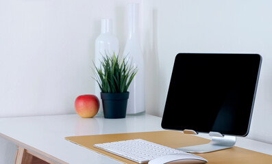 Mockup black screen tablet on stand holder with keyboard on white table, creative workspace concept.