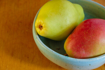 Two fragrant pears in a ceramic blue bowl on the wooden table. Copy space.