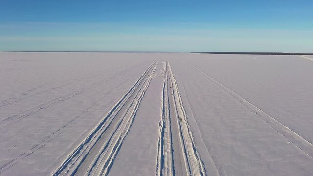 Aerial view of traffic on a ice road, cars driving on the frozen ocean - rising, drone shot