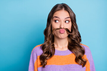 Fototapeta premium Portrait of attractive funny girl grimacing making fake mustache looking aside copy space isolated over bright blue color background