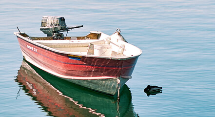 Dingy red moored on the water waiting for use on Como Lake 