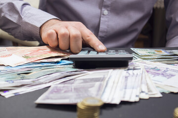 counts money on a calculator, coins and paper