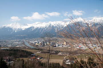 View of mountains covered with snow and city buildings in the valley. Panoramic landscape.