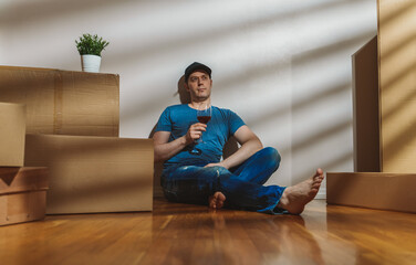 Tired man with glass of wine after moving to a new flat.