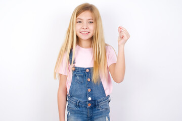 Fototapeta na wymiar beautiful caucasian little girl wearing denim jeans overall over white background pointing up with hand showing up seven fingers gesture in Chinese sign language QÄ«.