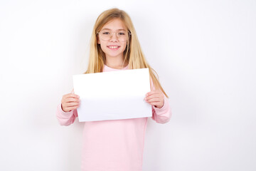 Naklejka premium Happy beautiful caucasian little girl wearing pink sweater Holding Empty Paper Board Advertising Offer Text Standing. Autumn Advertisement Banner.