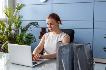 Portrait of blonde woman at the office with laptop computer