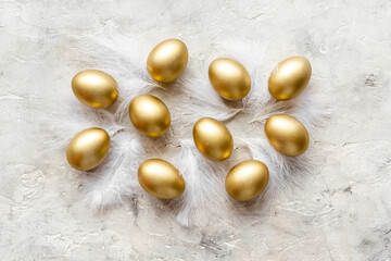 Golden Easter eggs with white feather. Easter decoration, top view