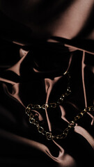 golden chain on dark brown background, bright light