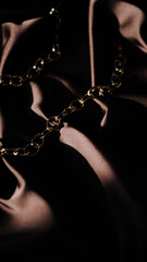 golden chain on dark brown background, bright light