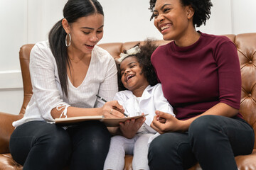 LGBT diversity Lesbian Couple Moments Happiness with her african girl laughing and drawing picture, LGBT lifestyle.