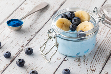 Close up of a blue spirulina super food yogurt parfait topped with blueberries and bananas.
