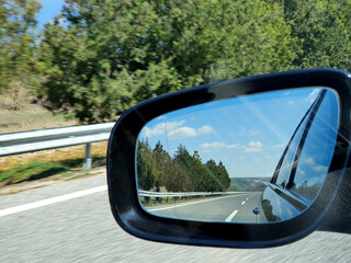 Obraz premium Landscape and road reflection in car rearview black mirror.
