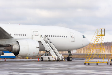 Airliner in a parking lot with a gangway for boarding passengers.