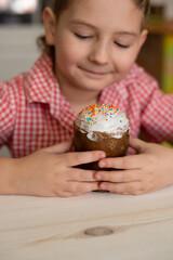 out of focus photo. Easter cake in the hands of a child on the background of a white wooden table