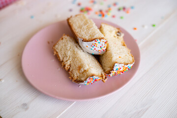 slices of Easter cake on a pink plate on a white wooden table background