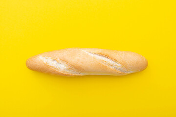 Baguette, French bread, loaf on yellow background as layout. Small French bread, top view, creativity picture.
