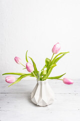 Bouquet of gentle pink tulips in ceramic vase on white background