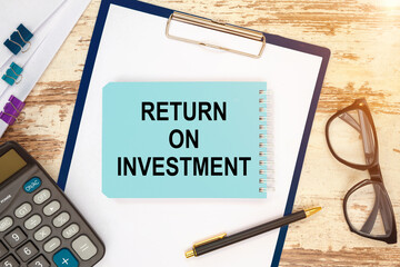 Notebook with text - RETURN ON INVESTMENT near office supplies.