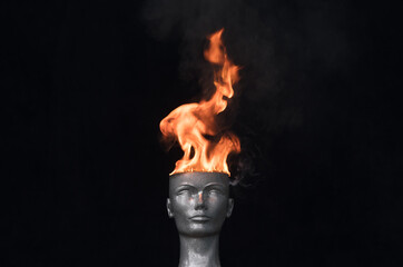 Fire on head.Mannequin head burns on a black background
