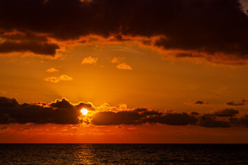 Dramatic sunset over ocean. Sky with clouds.