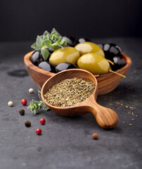 Thyme fresh and dry  in wooden spoon with olives on a black background. Olives with spices.