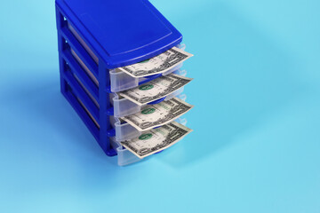 Box with open cells from which dollars are visible on blue background with copy space