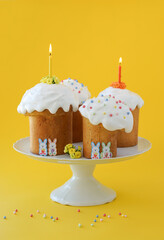 Easter Cakes. Easter celebration. Traditional Russian Kulichi on a yellow background with candles and flowers. 