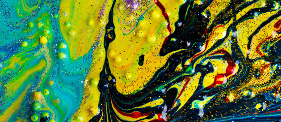 On the yellow liquid marble, blue and red streaks sprinkled with gold sparkles. Contemporary art. A...