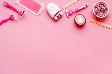 Flat lay of pink epilator with wax strips and razor. Spa cosmetic treatments.