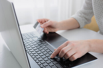 Fototapeta na wymiar Woman's hands holding credit bank card and using laptop computer at home Online shopping concept. Selective focus
