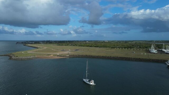 A high drone perspective moving over a small yacht anchored in a protected harbor located in the town of Bargara Bundargerg Queensland Australia
